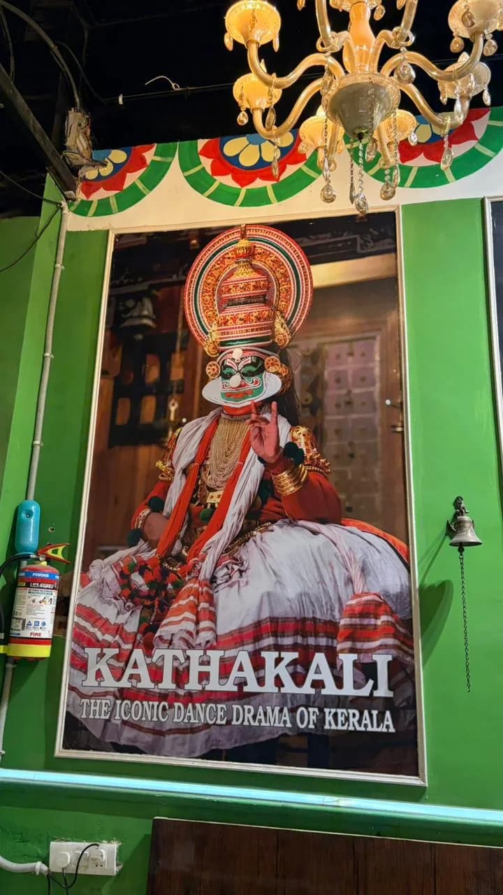 Kathakali print and brass bell on the green wall