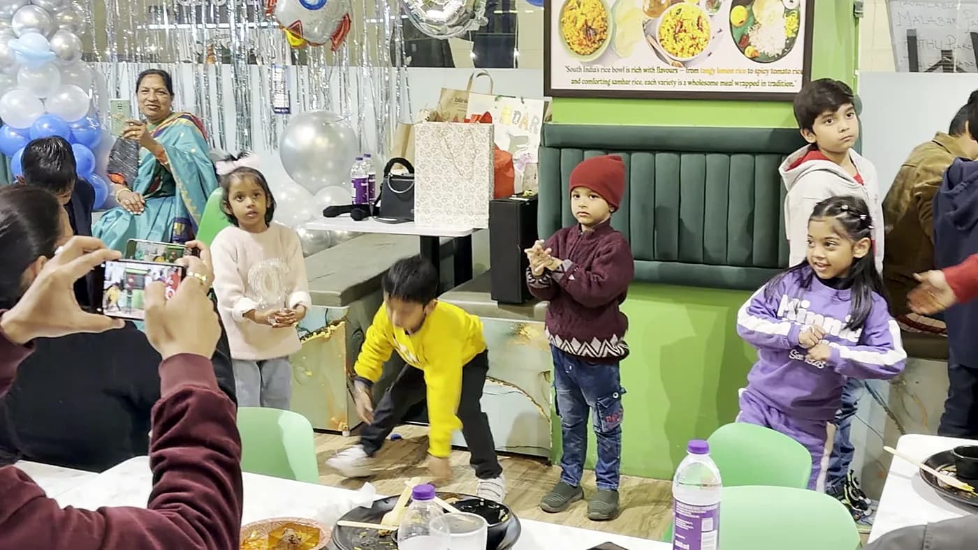 Children dancing at a birthday party, parents filming