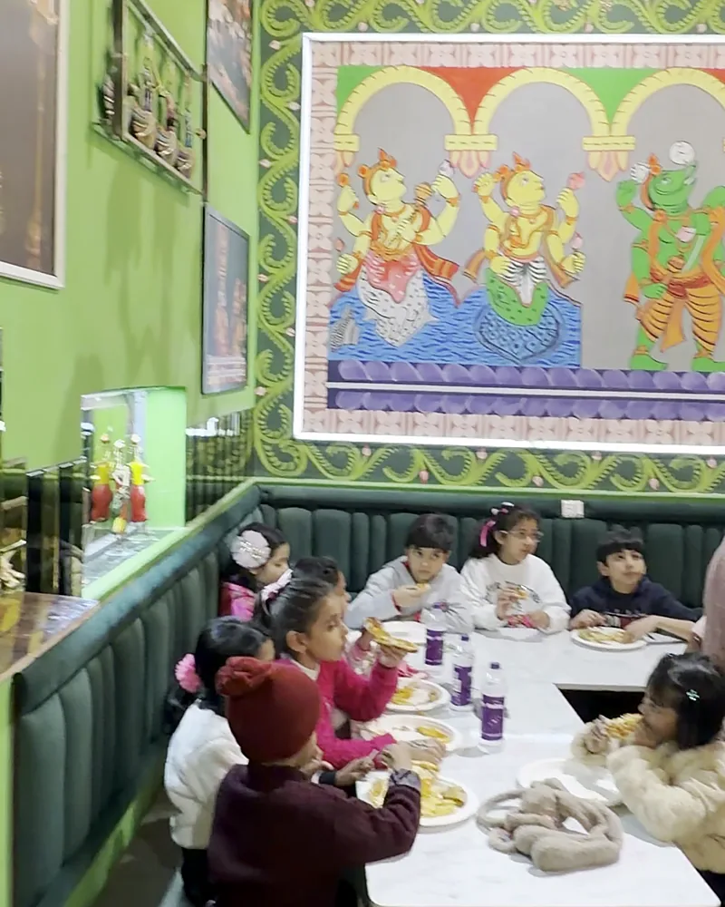 Children eating at a long table under the temple mural