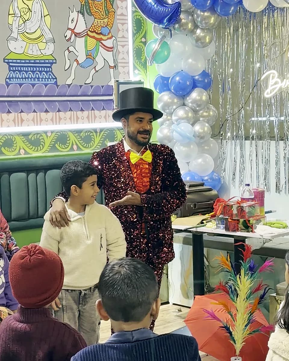 A magician in a top hat performing for children at a birthday party in our dining room